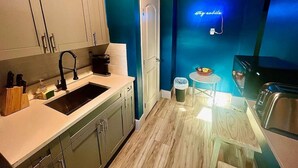 A compact kitchen with white cabinets, a black sink, and a neon sign on the wall. - Moody Stoody-O Near Las Olas Beach & Holiday Park (Fort Lauderdale)