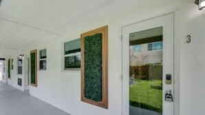 A hallway with doors, each with a window and a green plant.