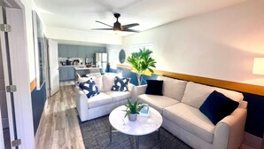A modern living room with a sofa, armchairs, and a coffee table. There is a kitchen in the background with cabinets and appliances. - Bahama Mama 2/1 in Las Olas & Holiday Park with Hot Tub! (Fort Lauderdale)