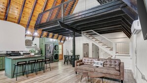 Een ruime loft met hoge plafonds, een keukenhoek, een eethoek en een woongedeelte met een bank en salontafel.