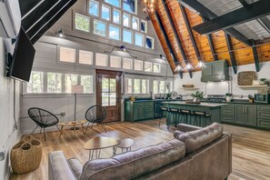 A spacious kitchen with high ceilings, wooden beams, and large windows. - A-frame in the cove  (Brookeland)