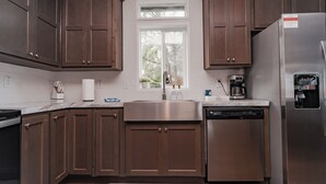 Een moderne keuken met bruine kastjes, roestvrijstalen apparatuur en een raam dat natuurlijk licht binnenlaat.