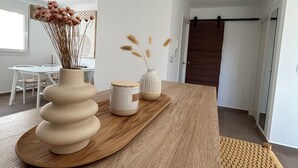 A modern dining area with a wooden table, two ceramic vases with dried flowers, and a woven chair. - NEW flat 50 meters from the sea !!! (Lo Pagán)