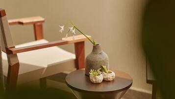 A wooden chair and a small table with a vase containing flowers and two small pots.