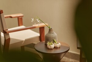 A wooden chair and a small table with a vase containing flowers and two small pots.