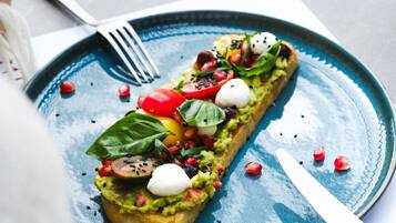 Plat amb puré d'alvocat, tomàquets, llavors de taronger i mozzarella sobre un plat blau.