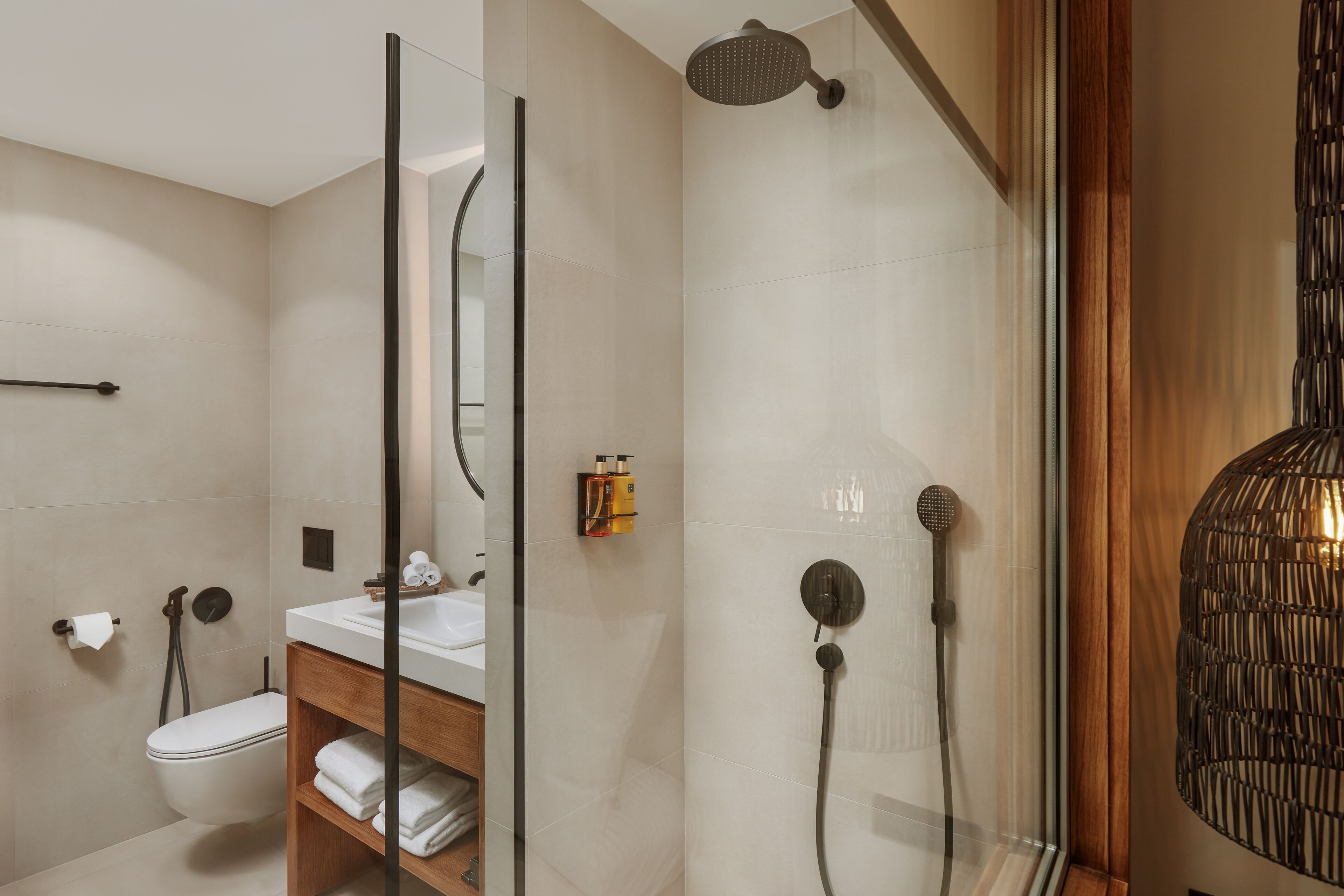 A modern bathroom with a glass-enclosed shower, a wooden vanity, and a toilet.