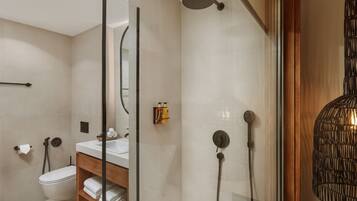 A modern bathroom with a glass-enclosed shower, a wooden vanity, and a toilet.