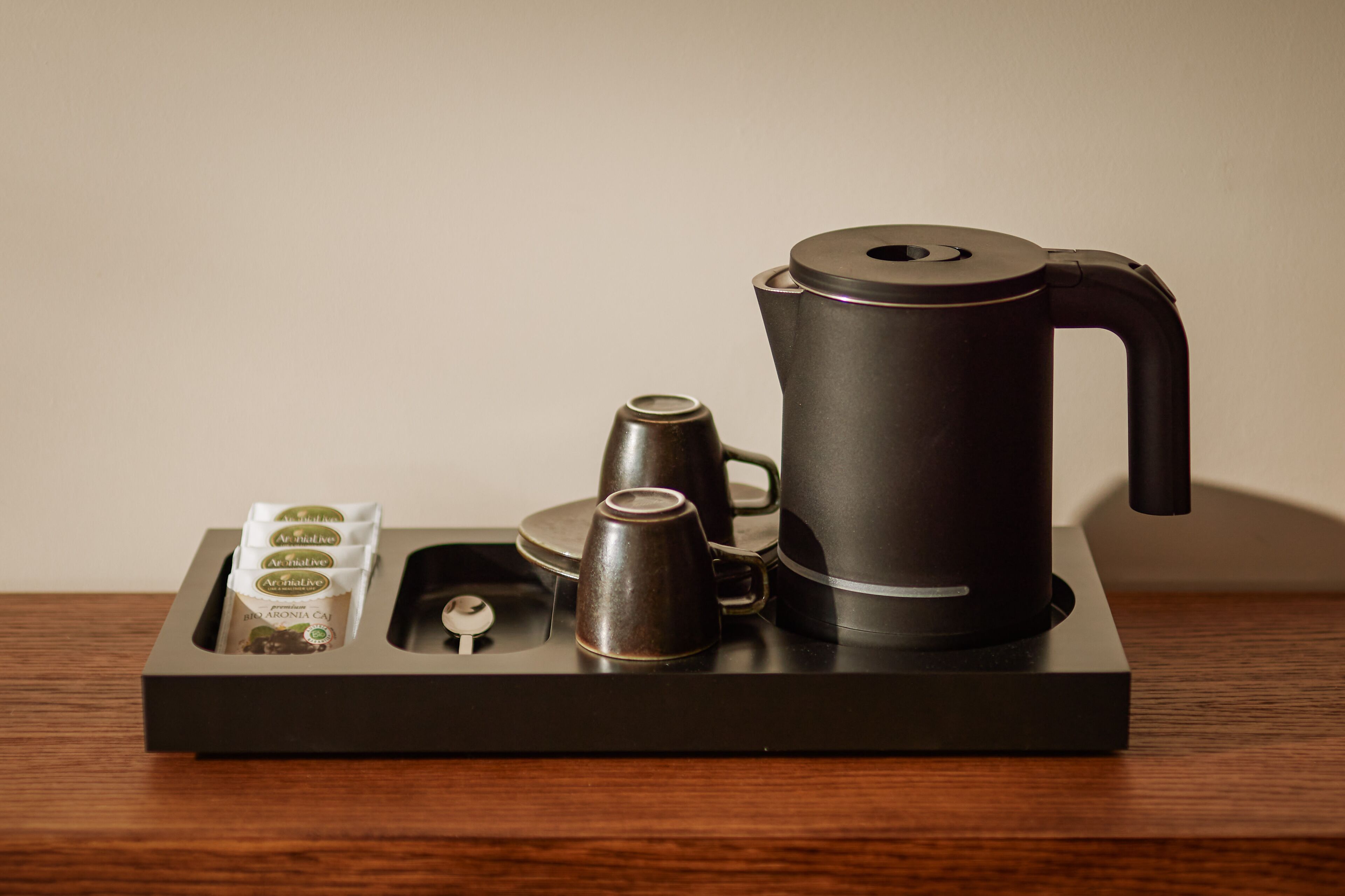 Une machine à café avec un plateau, une cafetière et trois tasses à café sur une table en bois.