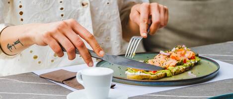 A person cutting a sandwich on a plate with a fork and knife.