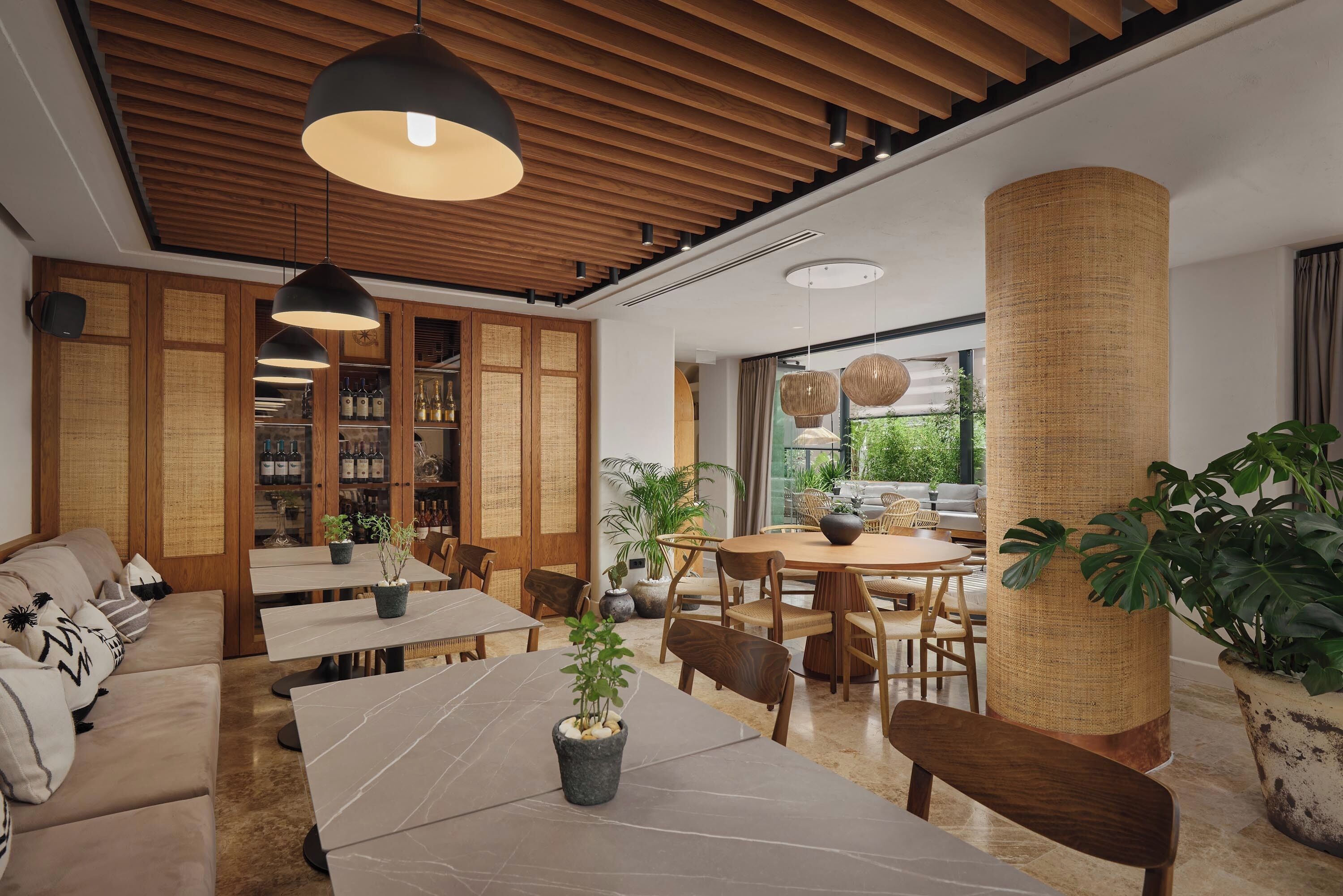 A modern interior with wooden ceiling panels, a dining area with tables and chairs, and a seating area with a sofa.