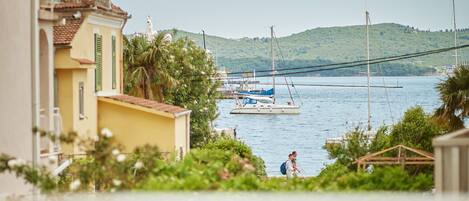 A balcony with a view of a harbor, including boats and a hilly landscape.