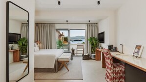 Una habitación de hotel moderna con una cama grande, un escritorio, una silla y vista al mar.
