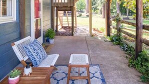 A covered patio area with wooden furniture and a patterned rug.