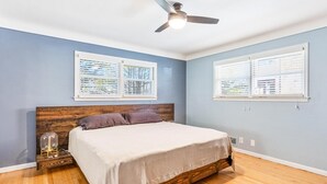 A bedroom with a wooden bed frame, a ceiling fan, and two windows with blinds. - Spacious 3 BR Modern Home in Grosse Pointe Park (Grosse Pointe Park)