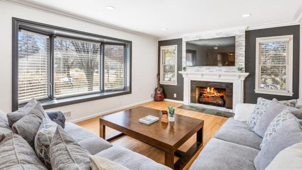 A living room with a fireplace, large windows, and a sofa. - Spacious 3 BR Modern Home in Grosse Pointe Park (Grosse Pointe Park)