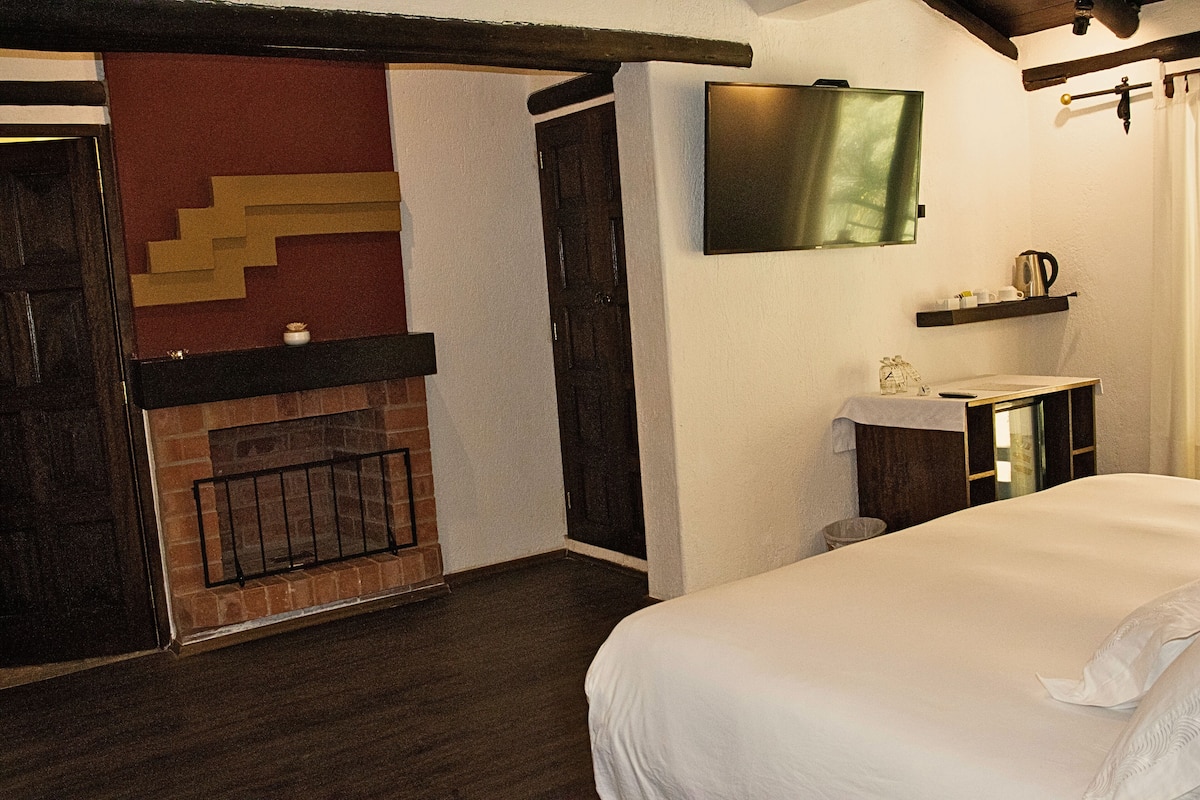 Ein Schlafzimmer mit einem Bett, einem Kamin, einem an der Wand montierten Fernseher und einem kleinen Regal mit Gegenständen.