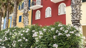 A multi-story building with balconies, palm trees, and flowering shrubs. - P011 - Porto Recanati, new studio facing the sea (Porto Recanati)