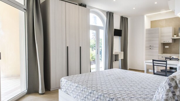 A modern bedroom with a large bed, a desk, and a kitchenette. - P011 - Porto Recanati, new studio facing the sea (Porto Recanati)