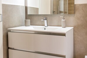 Une salle de bain avec un lavabo blanc, un miroir et deux distributeurs de savon.