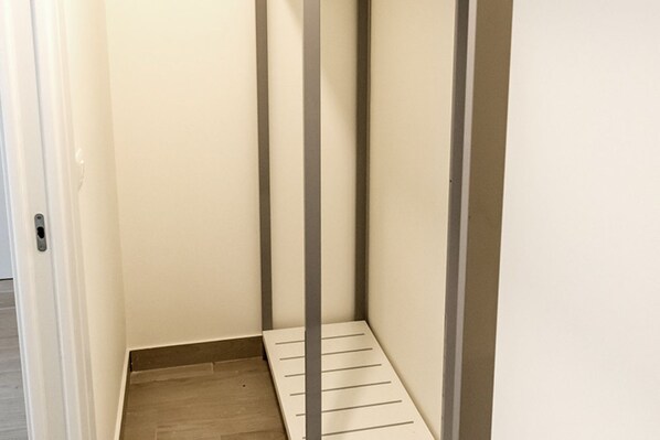 Un pasillo estrecho con suelo de madera y una puerta blanca a la izquierda.