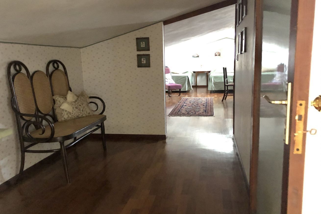 Um corredor com um banco, uma porta e vista para um quarto com cama e cadeira.
