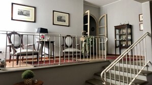 Eine Treppe mit Geländer, ein Essbereich mit Stühlen und Tisch sowie ein Schrank mit Glastüren.