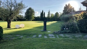 Eine grüne Außenanlage mit trittfesten Steinen, einem Baum und einem zylindrischen Gegenstand.