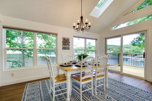 Un coin repas avec une table dressée pour quatre personnes, de grandes fenêtres et un lustre.