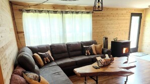 A cozy living room with a sectional sofa, a wooden coffee table, and a wood-burning stove. - Haywire Haus, Pictured Rocks, Hot Tub, ORV Trail (Shingleton)