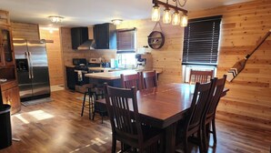 A wooden interior with a dining table and chairs, a kitchen area with appliances, and a wooden floor. - Haywire Haus, Pictured Rocks, Hot Tub, ORV Trail (Shingleton)