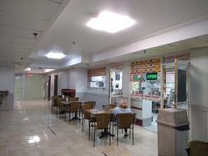 Un restaurante con mesas y sillas, un letrero de salida y una pizarra de menú.