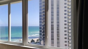 A window with a view of the ocean and a tall building in the background.