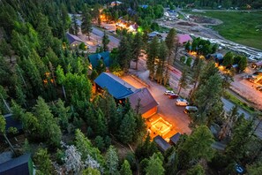 An aerial view of a forested area with a cluster of buildings, roads, and a river.