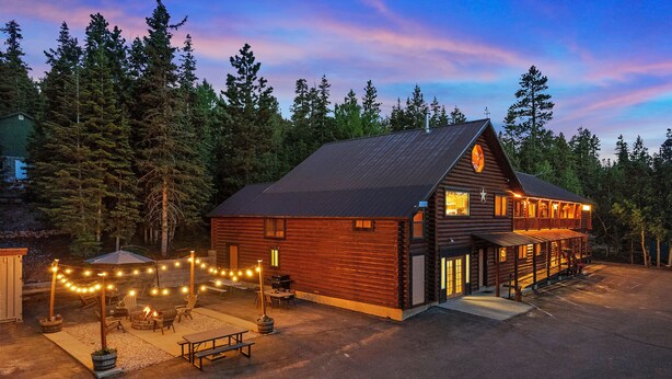 Eine Blockhütte mit Veranda, Sitzgelegenheiten im Freien und Lichterketten.