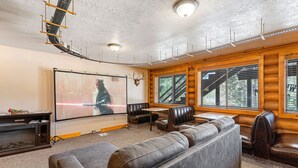 Ein gemütliches Zimmer mit großem Flachbildfernseher, Ledersitzmöbeln und Holzvertäfelung.