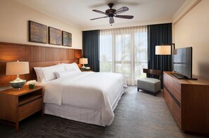 Relax in comfort with a large bed, nightstands, and a ceiling fan, surrounded by artwork and a large window.