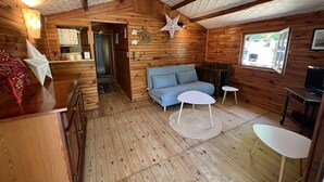 Ein gemütliches Blockhaus mit Holzvertäfelung, einem blauen Sofa, einem kleinen runden Tisch und einer Sterne-Dekoration an der Decke.