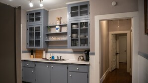 A kitchen with grey cabinets, a white countertop, and a 'Welcome' sign.