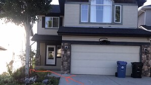 A two-story house with a garage, stone facade, and a driveway with orange markings.