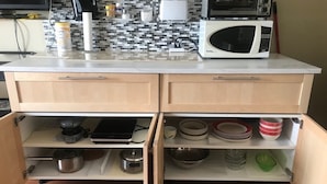 A kitchen with a microwave, toaster, and various kitchen utensils on the countertop.