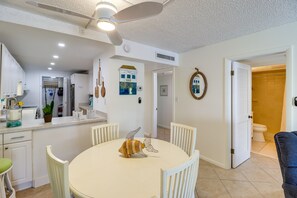 A dining area with a round table, white chairs, and a decorative fish sculpture. - Ocean-View Key Colony Beach Condo w/ Pool Access! (Key Colony Beach)