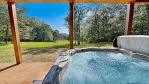A hot tub with a view of a grassy field and trees.