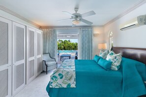 A bedroom with a bed, a ceiling fan, and a view of a pool and greenery outside.