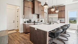 A modern kitchen with a central island, dark wooden cabinets, and pendant lighting.