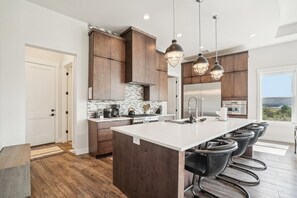 A modern kitchen with a central island, dark wooden cabinets, and pendant lighting.