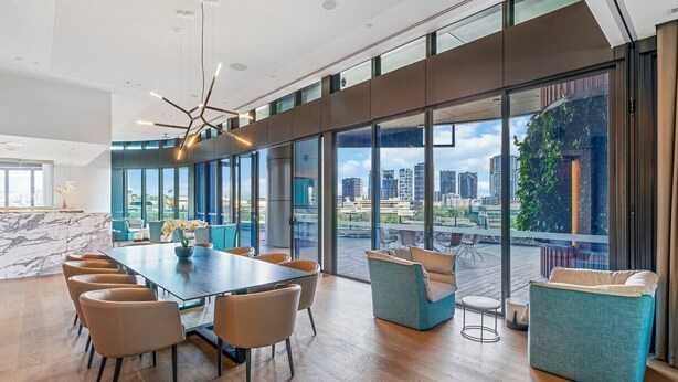 A spacious conference room with a large table and chairs, large windows offering a city view, and a modern ceiling design.