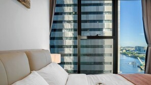 Une chambre d’hôtel dotée d’une grande fenêtre donnant sur un paysage urbain et une rivière.