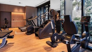 Une salle de sport moderne équipée de tapis de course, de vélos elliptiques et d’un rameur.
