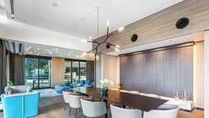A modern conference room with a long table, white chairs, and a blue sofa.